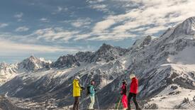 Groupe de skieurs à l'arrêt observant une chaîne de montagnes enneigées